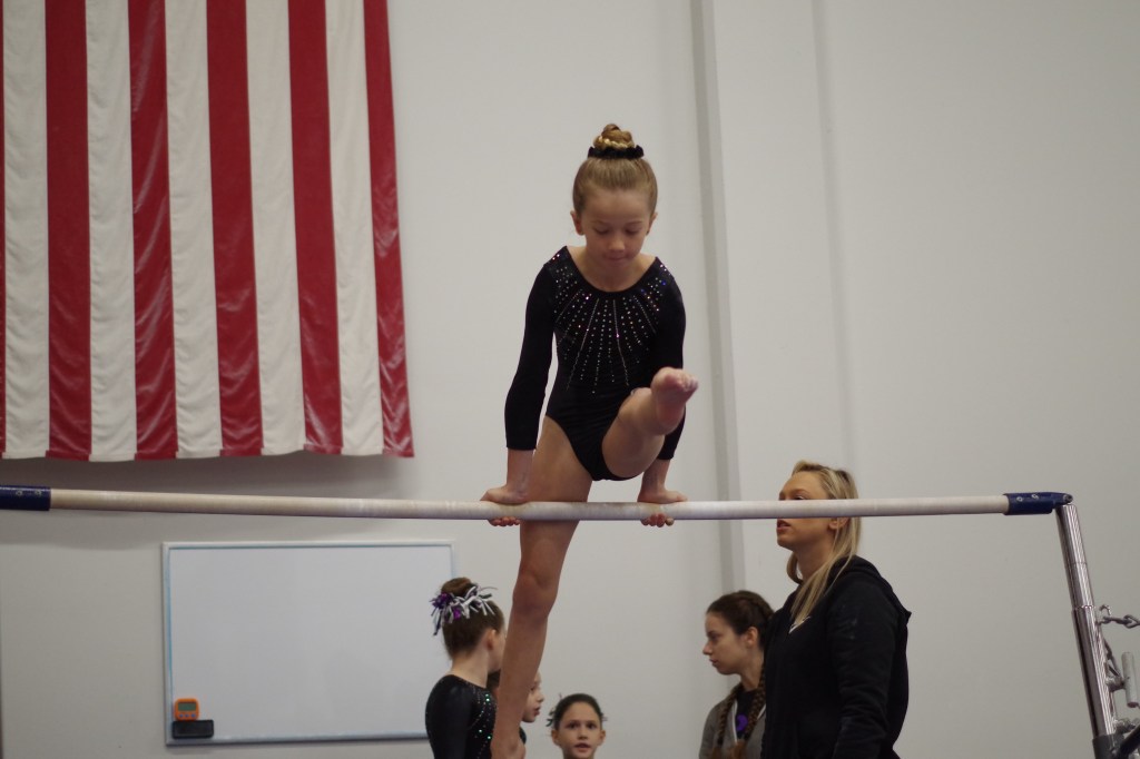 Practicing her mill circle on bars at a gymnastics meet
